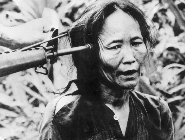 A Vietnamese civilian with a gun pointed at the side of her head. (Photo by Keystone/Getty Images)
